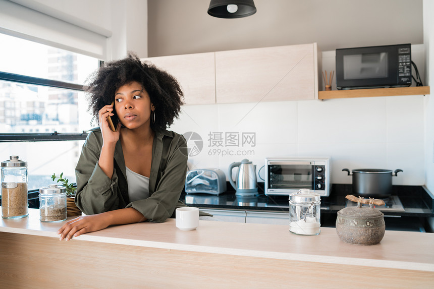 afro女人的肖像在电话上说和一杯咖啡在家里通信概念图片