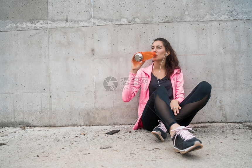 以灰色背景体育和健康生活方式进行训练后一名运动妇女饮用水的肖像图片