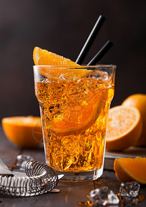 在高球玻璃中用橙色片和黑底的冰块来装有aperolsitz夏季鸡尾酒背景图片