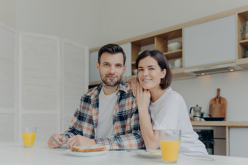 已婚夫妇在厨房桌上吃早餐的肖像图片