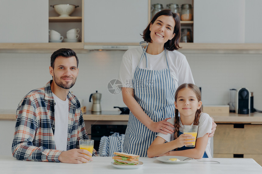 父亲母及其小女儿心情良好一起度过时间准备厨房聚在一起吃早餐享受家庭气氛图片