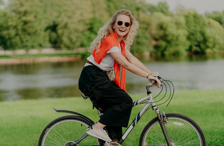 身穿休闲服的女子骑着自行车在河道边图片