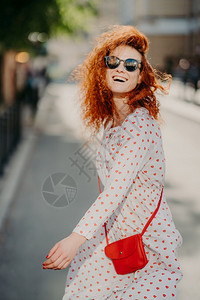 一地红包无忧虑的红发女人笑得很开心在城市户外自由度日穿太阳眼镜长袖衣服带红包玩得开心享受娱乐时间人与生活方式背景
