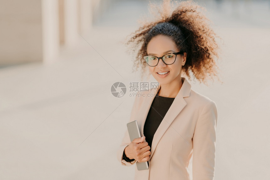 美籍女商人在户外漫步带着触摸板穿正规衣服戴光观眼镜在头上微笑会后享受闲暇时间图片