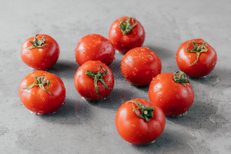 成熟的西红柿和刚在花园上采摘的露有机食品概念灰色背景的樱桃西红柿图片