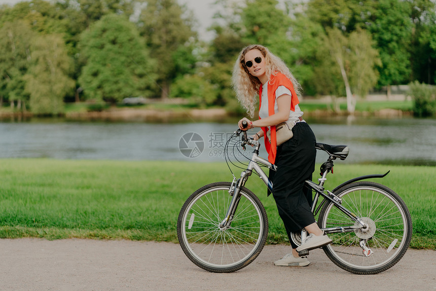 漂亮年轻女子骑着运动自行车在路边停下图片