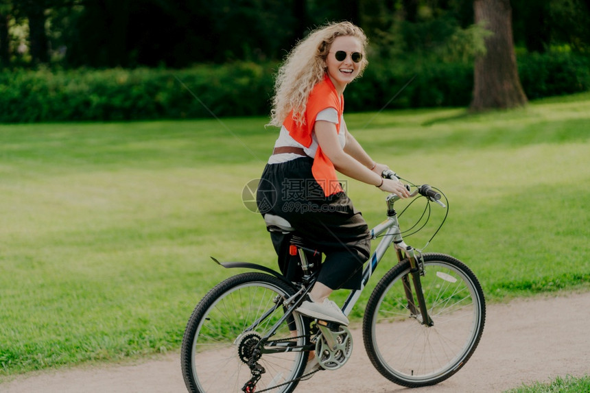 快乐女子骑着自行车在公园内图片