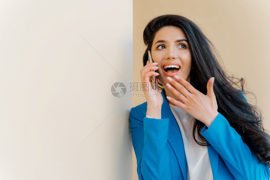 积极商业女人张开对感兴趣的嘴摸下巴看一眼对谣言着迷与亲密朋友有电话交谈对最新闻流言八卦穿正式蓝色服装图片