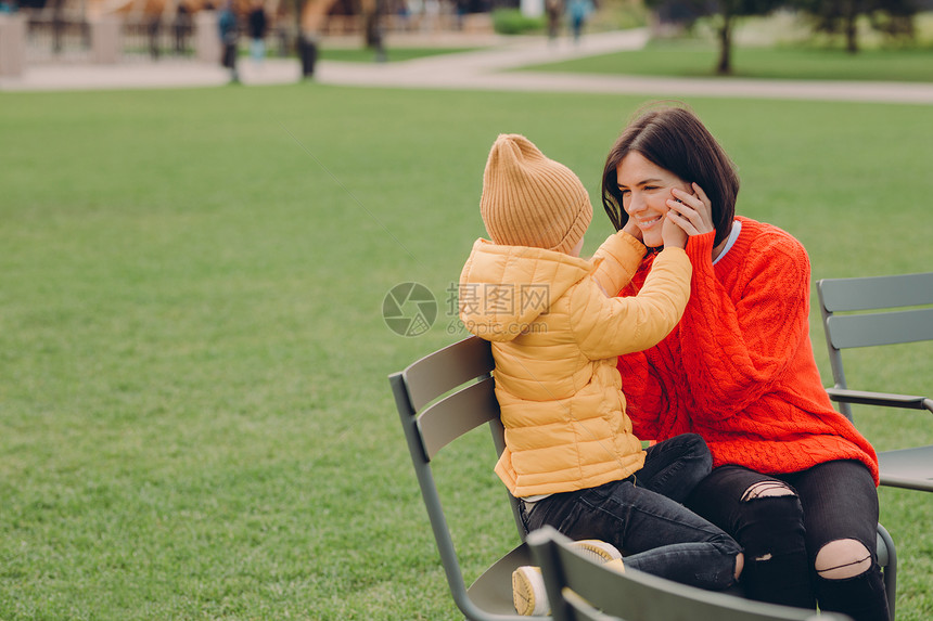 快乐的年轻妈和女儿坐在空旷的草地上图片