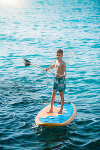 划船赏月男孩起立在海边的船桨板上起立在船桨背景