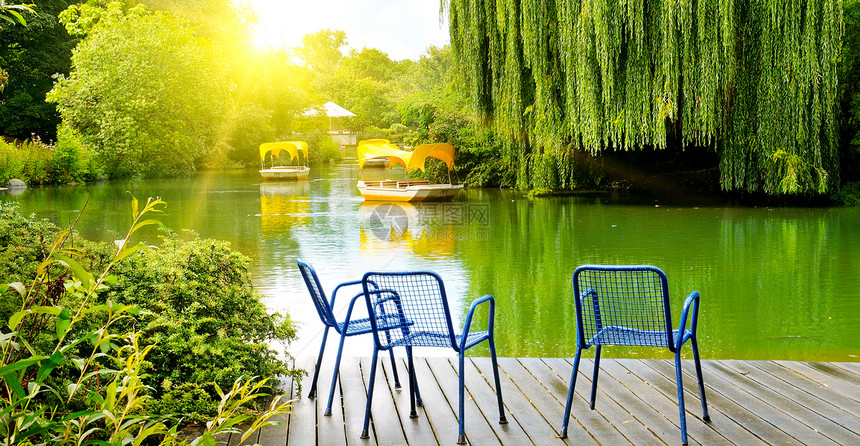 娱乐公园湖边游艇木头码有椅子和太阳休息室夏日光明媚图片
