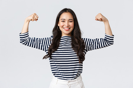 吹嘘强烈而自信的亚洲女柔韧biceps吹她的完美形状吹在注册体育馆会员资格之后吹肌肉运动和感觉强烈生活方式人们的情绪和随意概念强烈而背景