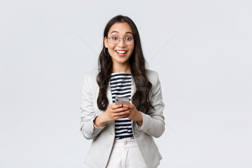 商业金融与就女成功创者概念快乐的亚洲女商人办公室经理用智能手机笑地看喜悦的相机快乐亚洲女商人办公室经理用智能手机看喜悦的亚洲女商图片