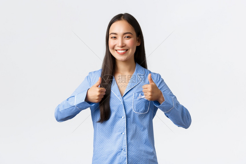 穿着蓝睡衣的快乐笑年轻女孩看上去很满意表现得非常满意表现得非常好或出色说做得好或站在白色背景上感到高兴图片