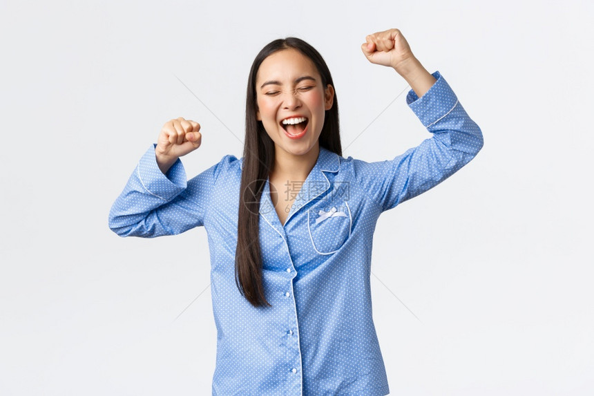 欢乐地庆着穿蓝睡衣的亚洲妇女欢呼笑和乐地乐的图片