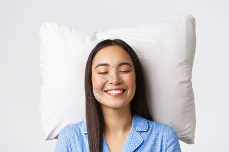蓝色睡衣睡在枕头上穿着蓝睡衣闭上眼睛微笑白梦或夜间睡觉想象一些可爱白色的背景躺在枕头上白色的背景背景