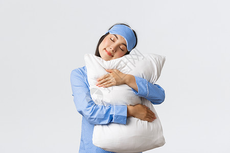 睡着面罩和衣的女孩着闭眼睛拥抱舒适的枕头睡衣着在有生产能力的白天后感到愉快的床上睡觉着的女士的快乐背景图片