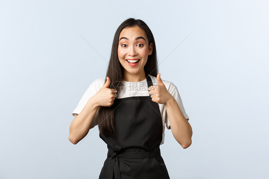咖啡店小商业和启动概念兴奋的笑像一个女服务员般的笑批准新菜单可爱女酒吧咖啡师在黑色围裙展上大拇指支持喜欢或同意兴奋的笑像一个女服图片