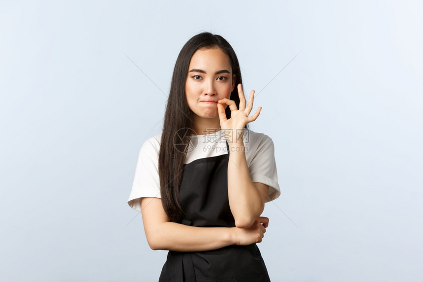 咖啡厅小商业和开办概念严重可爱的韩国咖啡会厅女雇员承诺保守秘密拉链或锁嘴唇站在黑色围裙中站在咖啡厅小商业和开办概念图片