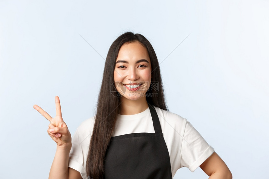 咖啡厅小商业和开办概念友好可爱的亚洲女雇员黑围裙内咖啡厅工作人员展示和平标志对客户微笑表达积极态度小企业和开办概念友好的亚洲女雇图片