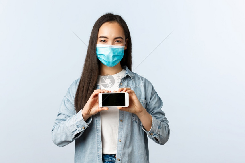 女青年疫情期间戴着口罩拿着手机图片