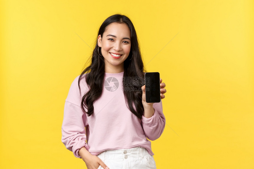 人们的情感生活方式闲暇和美丽概念笑的亚洲女20岁展示智能手机显推荐应用程序或移动游戏在屏幕上广告黄色背景人的情感休闲和美丽概念2图片