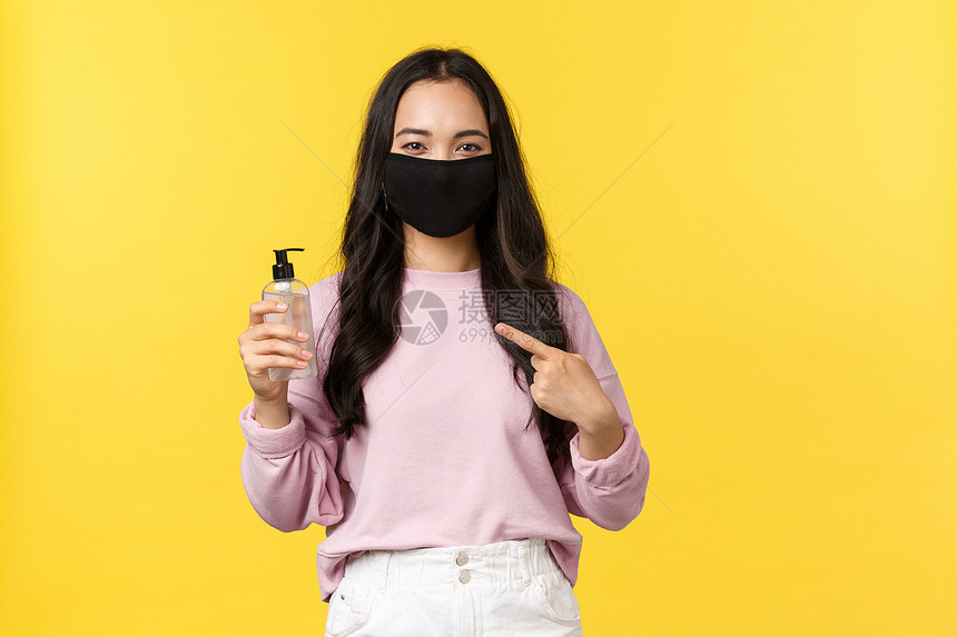 19岁社会维生的活方式防止传播的概念脸面遮罩指着手防疫剂在科罗纳流行期间照顾个人卫生黄色背景19岁防止传播的概念面罩指着防疫剂黄图片