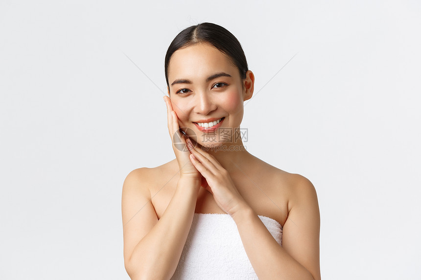 穿着毛巾的美丽亚洲女孩站在浴室的白色背景上穿着毛巾的漂亮女孩在浴室的白色背景上穿着毛巾的年轻女孩图片