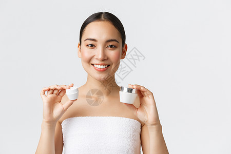 美貌个人护理温泉沙龙和皮肤护理概念美丽的亚洲女在浴巾上露出两个面部和眼霜微笑以建议的方式使用水合养肥皮肤护理治疗美貌养肥皮肤护理背景图片