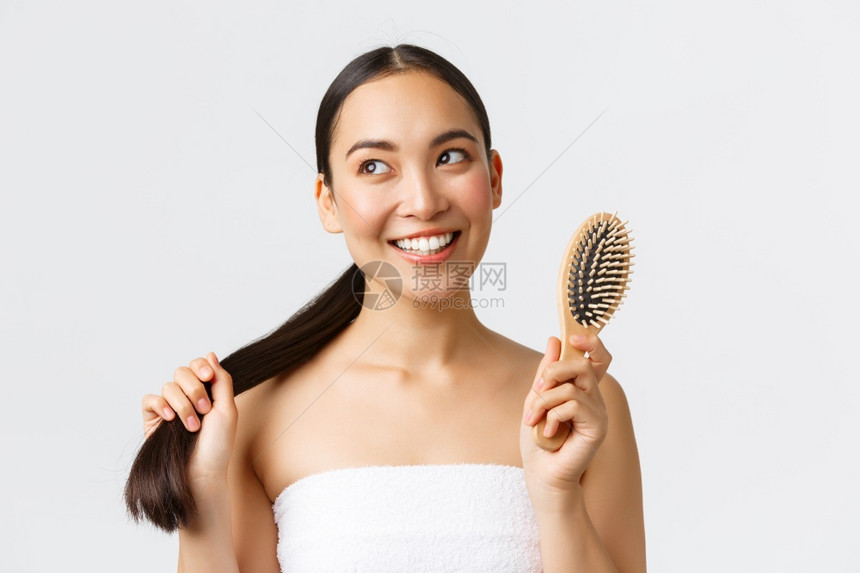 美丽的亚洲女孩穿着浴巾带可爱的笑容用白色背景的刷子马尾辫美丽发洗水和头护理概念美丽的亚洲女孩用白色背景的刷子马尾辫图片