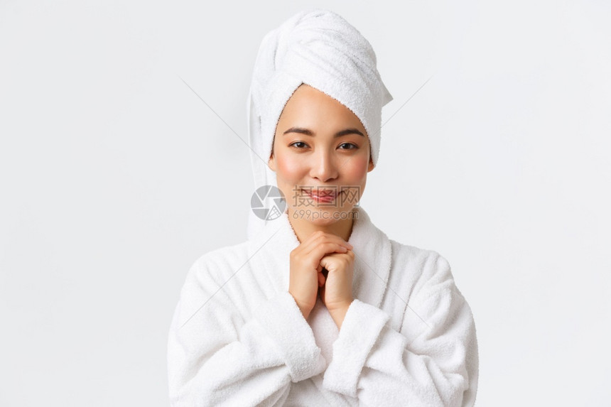 身穿浴袍和毛巾的有吸引力亚洲女孩带着钦佩或喜悦微笑着可爱站在白色背景上充满希望身穿浴袍和毛巾的有吸引力亚洲女孩站在白色背景上充满图片