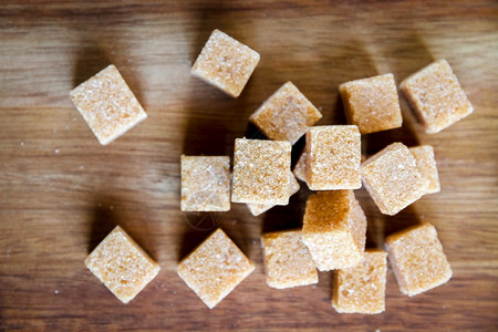 木制切板上的甘蔗糖方块顶部视图棕制甘蔗糖方块在切割板上图片
