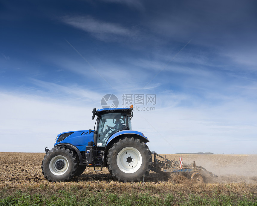 夏季在蓝天空下弗朗特以北的兰蓝天为的田地上用拖拉机的农民图片