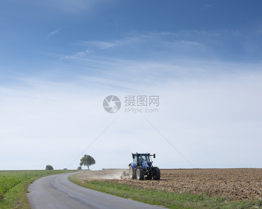 夏季在蓝天空下弗朗特以北的兰蓝天为的田地上用拖拉机的农民图片