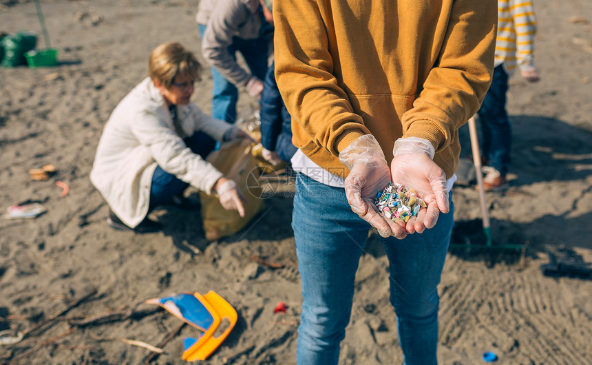 在海滩上展示微塑料的年轻人手在海滩上展示微塑料的细节在海滩上展示微塑料的手图片