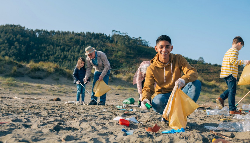 年轻人在海滩上和一群志愿者起捡垃圾图片