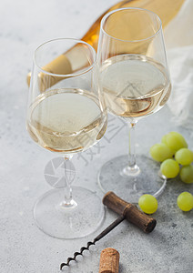 两杯白自制的夏日清酒配葡萄和瓶放在浅色桌底高清图片
