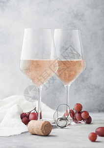 粉红玫瑰杯由自己制的夏日清酒配有衣柜葡萄和放在浅色桌底图片