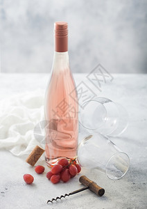 瓶装粉红玫瑰葡萄酒和空杯子装有开瓶器和光桌底的衬衣图片