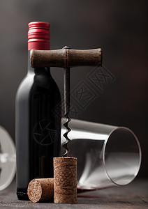 在木本底有玻璃和一瓶红葡萄酒的老旧软木瓶子高清图片