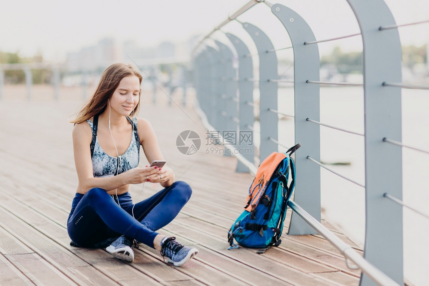 喜欢运动和积极生活方式穿着上衣和脚跟在手机上阅读互联网正面消息步行长途停留听音乐图片