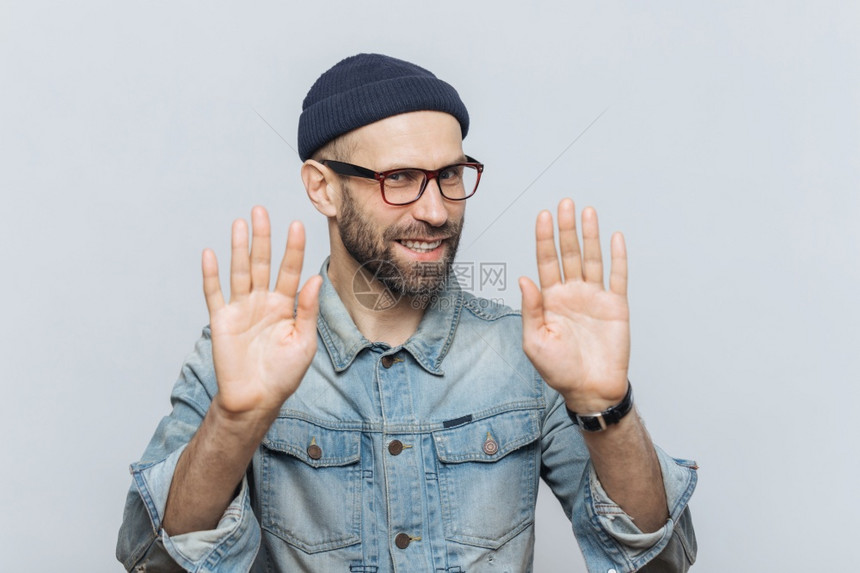 不要打扰我快乐的男喜悦外表展示停止牌要求不和他说话戴着时尚的帽子和眼镜孤立于灰色工作室背景图片