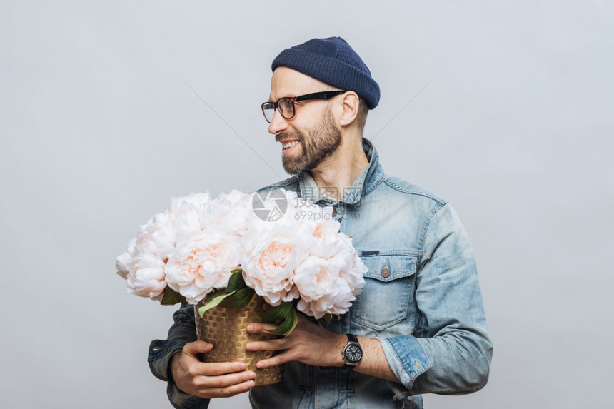 欢乐的胡须男子横向镜头外看却拿着一束白花心情好得像和女友约会一样给她做礼物与白人背景隔绝图片