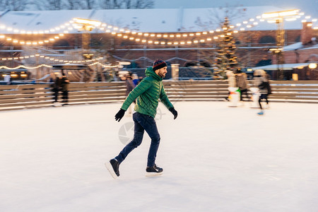 穿着绿色夹克溜冰鞋滑过冬假使用展示自己的专业精神享受寒雪天气图片