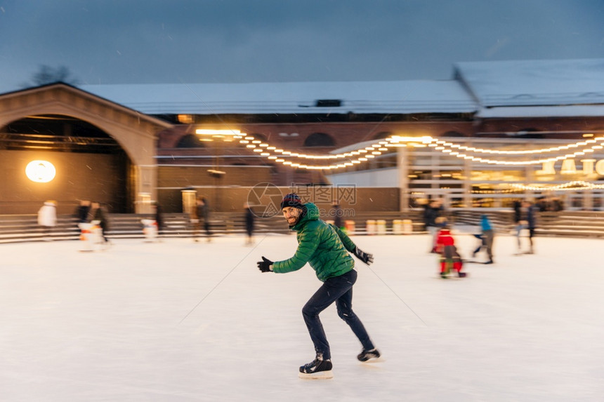喜悦的胡子男在圣诞节时花间在盛大的冰场上装饰着灯光滑冰玩得开心享受他的爱好着寒冷的冬季天气人休闲积极的生活方式概念图片