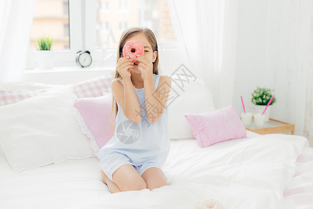 漂亮的小女孩拿着美味甜圈在睡房里穿衣准备吃早餐图片