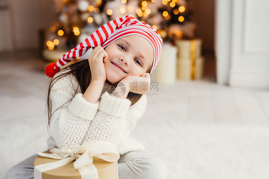 美丽的小孩子在客厅里摆姿势现在的礼物很瘦有快乐的表情很高兴从父母那里得到惊喜在家庭圈子里度过节日图片