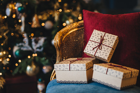 包着礼品盒的图片放在椅子上与装饰新年树背景的相配假期准备美丽圣诞树带花冠的圣诞树和室内的礼物背景图片
