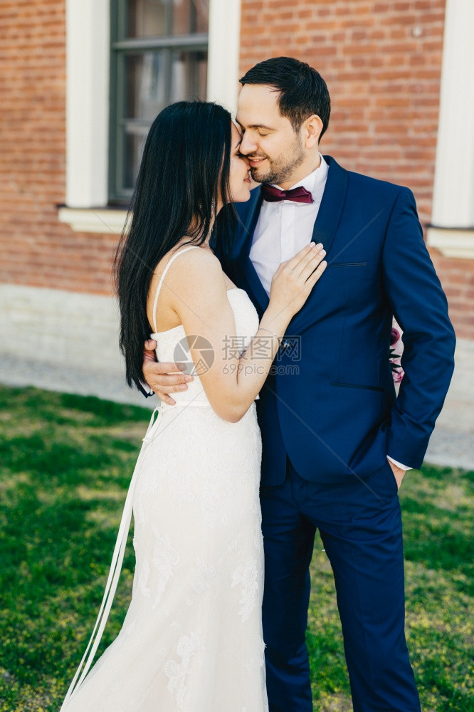 结婚的新娘和郎亲吻表达真实的情感爱和华丽的已婚夫妇在绿草上露出户外图片