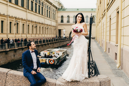 可爱的新娘长发黑穿着婚纱拿美丽的花团站在桥上图片